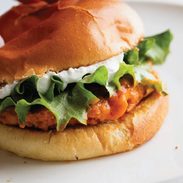 Buffalo chicken burgers on a bun with lettuce and whipped feta spread.