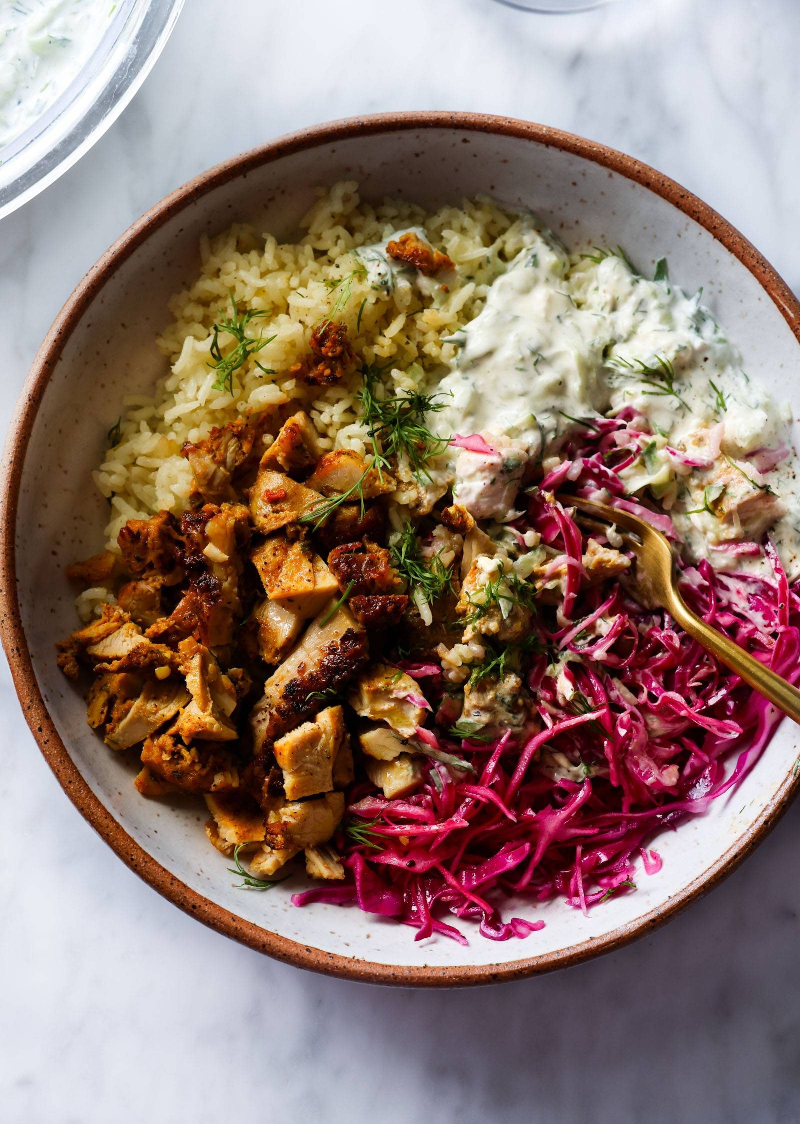 Chicken shawarma in a bowl with lemon rice and slaw.