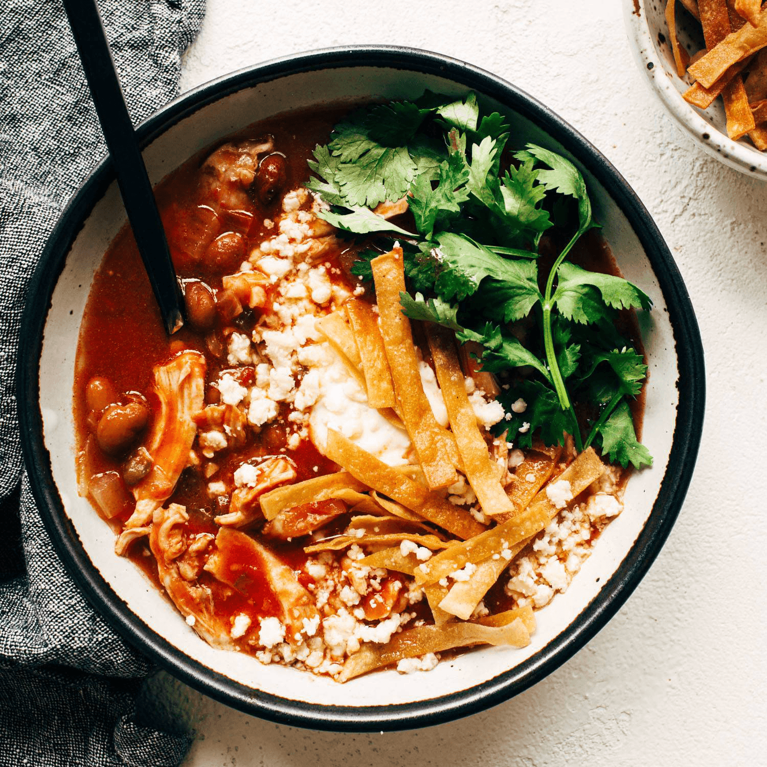 Chicken tortilla soup in a bowl topped with cheese and cilantro.