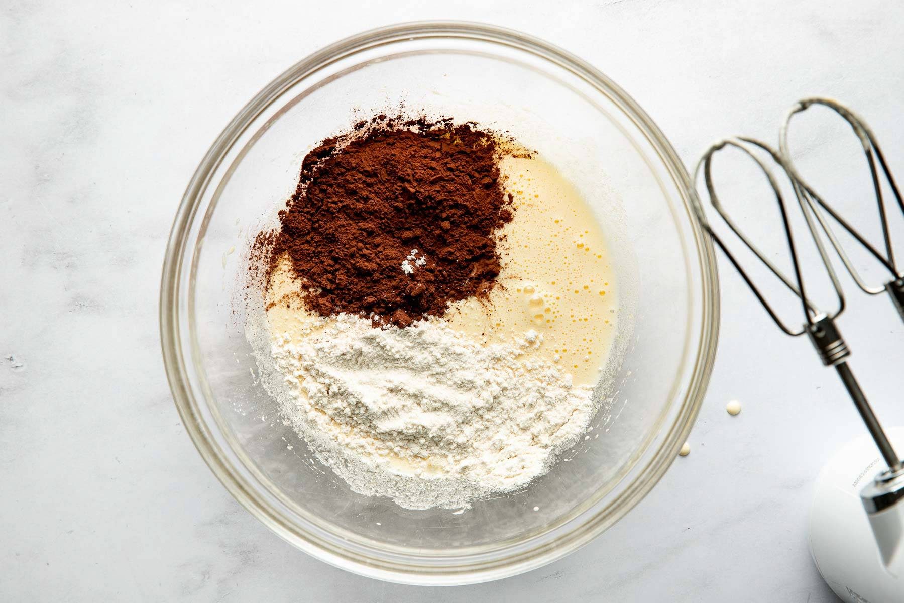 Adding cocoa powder and flour to the bowl.