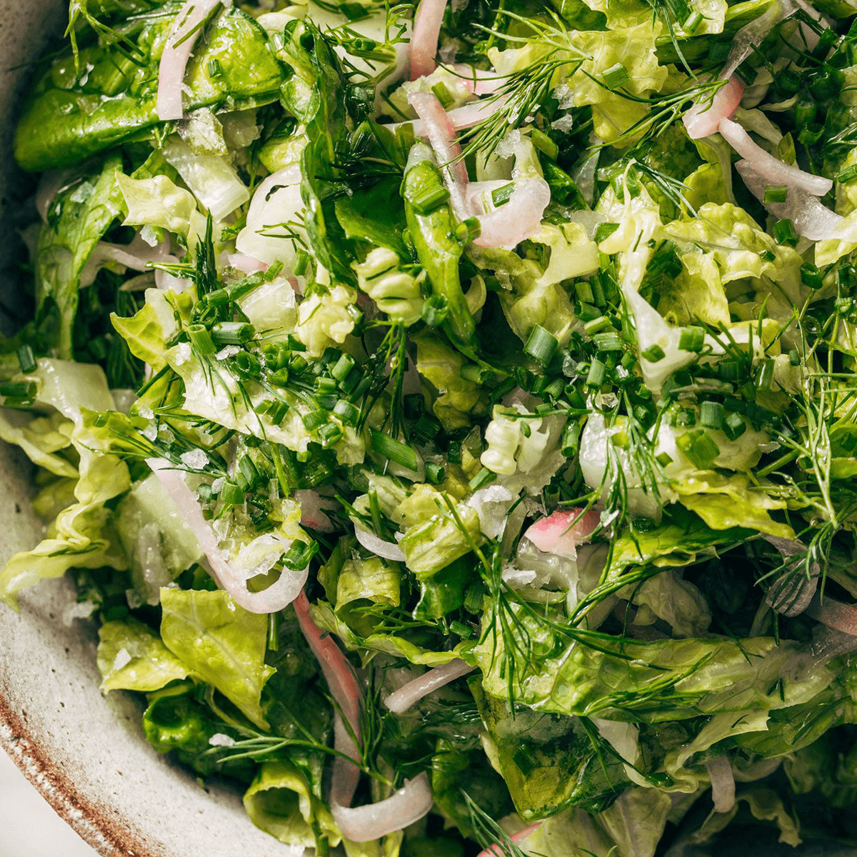 Green salad in a bowl with herbs.