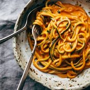 Roasted red pepper pasta in a bowl with zucchini noodles.