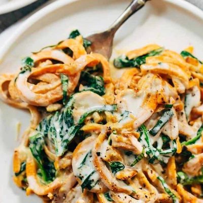 Creamy Spinach and Sweet Potato Noodles on a plate with a fork.