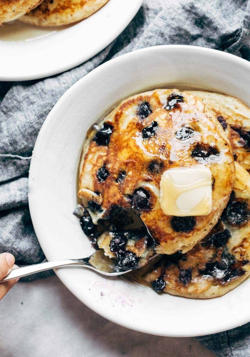 Blueberry pancakes on a plate with syrup and butter.